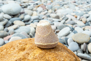 Singular Striped Stone Poised on Big Stone Amidst Pebbles