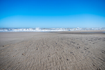 Fototapeta na wymiar Serene Beachscape with Textured Sands and Crashing Waves