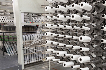 Factory equipment in perspective. Rows with coils of polypropylene threads for weaving cloth. Automatic machine. Nobody.