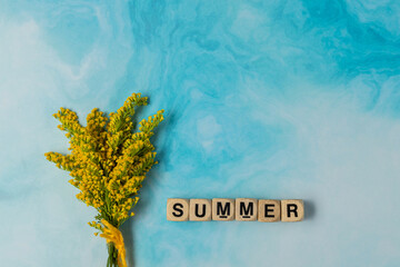 boggle cubes letters summer word on blue sky background and bouquet of yellow flowers and negative...
