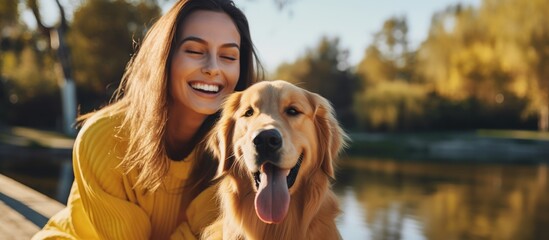 A happy woman wearing a yellow sweater is shown hugging a golden retriever dog in a casual outdoor setting. The woman and dog are enjoying a moment of affection and companionship.