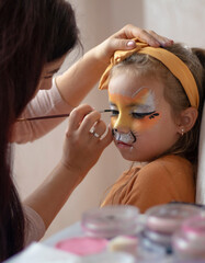 childrens makeup face paint drawings Girls face painting. Little girl having face painted on birthday party. closed eyes. kids birthday party. High quality photo