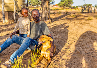 african village man with braids playing with his daughter and the dog