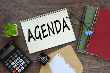 Agenda on the work desk there is a red notepad, an envelope, a calculator. text