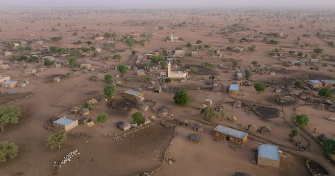 Aerial fly over.  A typical farming village in the barren landscape of the Sahel region, Sahara Desert, Senegal. Drought, Climate Change, Desertification