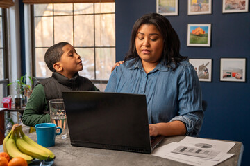 Hispanic woman working from home being distracted by her son