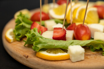 Fresh summer fruit kebab on a slate plate. vitamin sweet food background. Delicious appetizers with cheese and mix ingredients 