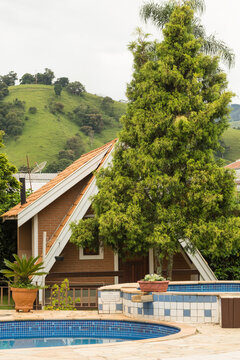 Chalé de alvenaria com piscina no pé da serra cercado de muita vegetação e árvores. 