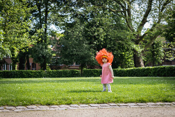 Portrait of a girl with a Belgian flag wig in the park.