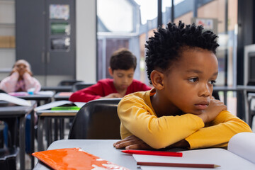 African American boy in a yellow shirt looks sad in a classroom setting with copy space