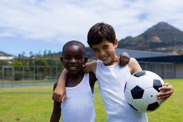 Biracial boy and African American boy smile, holding a soccer ball in school