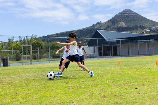 Biracial boy and African American boy play soccer outdoors in school