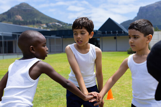 Biracial and African American boys join hands in a game outdoors in school