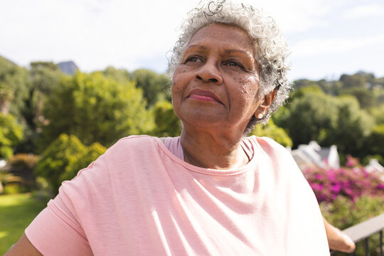 Senior biracial woman with short gray hair gazes thoughtfully in an outdoor setting - Powered by Adobe