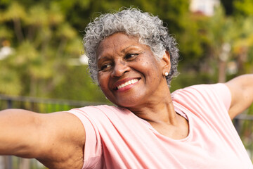 Senior biracial woman with curly gray hair smiles outdoors