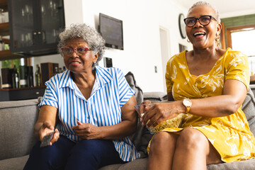 Senior African American woman and senior biracial woman sit together on a couch at home