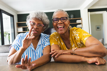 Senior African American woman and senior biracial woman are sharing a joyful moment on video call at - obrazy, fototapety, plakaty