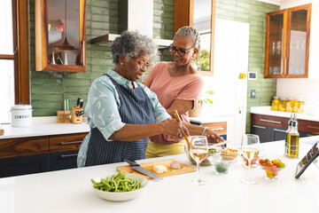 Senior African American woman and senior biracial woman are cooking together in a kitchen