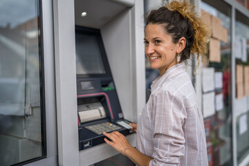 woman using credit card and withdrawing cash at the ATM