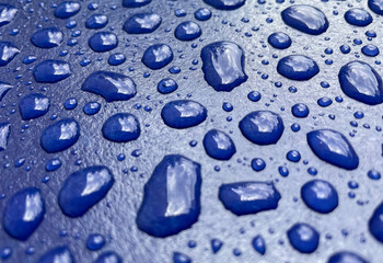 Den Haag, Netherlands - July 25 2021: water drops are laying on the roof of a freshly painted blue car