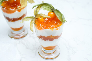 Close up of layered dessert with protein yoghurt and physalis fruit in a glass jar