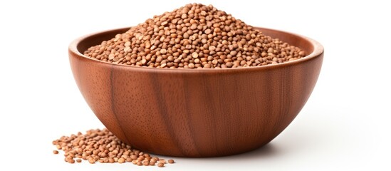 Fototapeta premium A wooden bowl sits on a white background, filled with raw brown buckwheat seeds. The seeds are small, shiny, and tightly packed within the bowl, creating a textured and organic look.