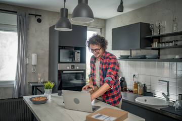 one man checking box of received package or product at home - obrazy, fototapety, plakaty