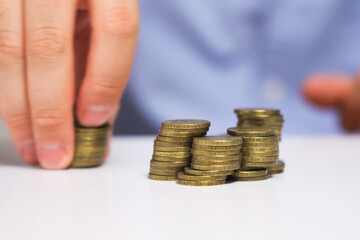 A man's hand moves stacks of coins across the table. Creative concept of stock market movement.