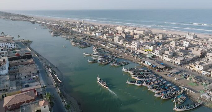 High aerial fly over.   Colourful pirogue boats lie anchored in the polluted Senegal River. Plastic pollution, Saint-Louis, Senegal, Unesco World Heritage Site