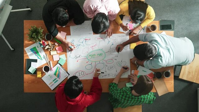 Group of business people writing and making mind map to brainstorming marketing idea at meeting. Top aerial view of investor sharing plan or strategy by using colorful marker. Time lapse. Convocation.