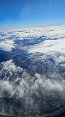 an aerial shot for majestic mountain ranges covered in snow and powerful clouds and blue sky in California USA