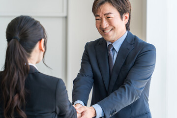 企業のオフィス・会議室で握手をして契約を結ぶ中高年ビジネスマン
