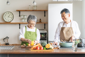 家のキッチンで一緒に料理・家事を楽しむ高齢者夫婦・シニアカップル
