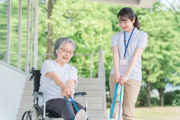 チューブトレーニングする高齢者女性と理学療法士（リハビリ・運動）
