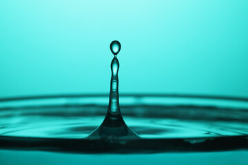 Splash of clear water with drops on turquoise background, closeup
