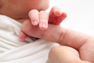 Close-up of baby's small hand, head, ear and palm of mother. Newborn baby after birth tightly 