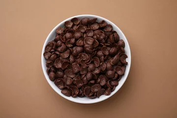 Fotobehang Breakfast cereal. Chocolate corn flakes in bowl on brown table, top view © New Africa