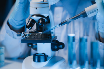A scientist is studying samples using a microscope to study and develop the field of microbiology,...
