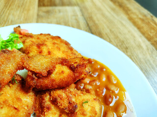 Partial view of plate with Breaded fillet of chiken breast on traditional Brazilian meal known as  prato feito on the wooden restaurant table .