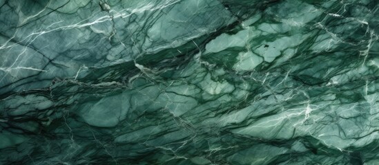 A detailed close-up of a green marble texture with intricate white curly veins. This surface showcases the unique patterns and colors of granite stone, ideal for ceramic wall tile and flooring designs