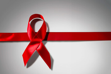 red ribbon in the shape of mourning on a gray background