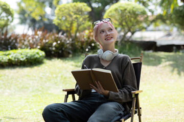 Cute and positive Asian woman recording data on a tablet or jotting down some ideas while sitting...