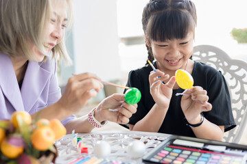 Little girl and mother painting on Easter eggs, Happy easter concept