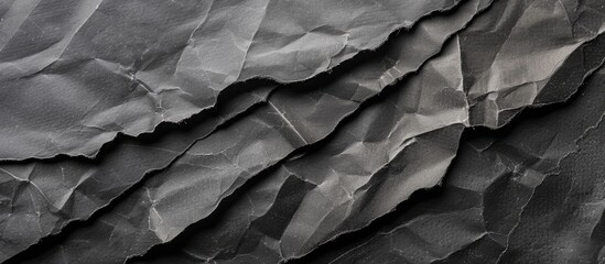 A close-up view of a black and white wrinkled paper, creating a textured background with ample space. The paper appears aged and worn, showcasing its unique pattern of creases and folds.