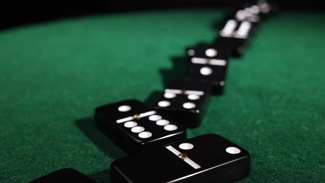 Black domino tiles falling collapsing on green table 6