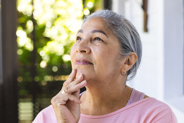 Senior biracial woman with grey hair looks thoughtful, touching her chin