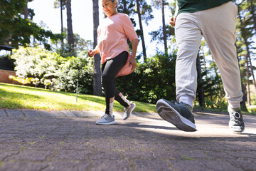 Senior biracial woman and man are walking briskly in a park with copy space