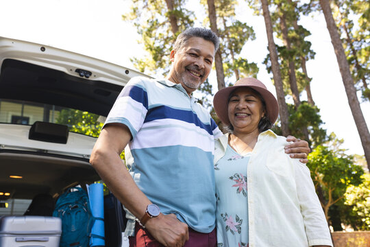 Senior biracial couple smiles, ready for a road trip with their car's trunk open