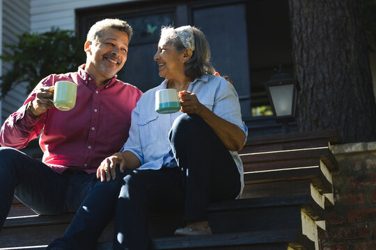 Senior biracial woman and biracial man enjoy coffee outdoors - Powered by Adobe