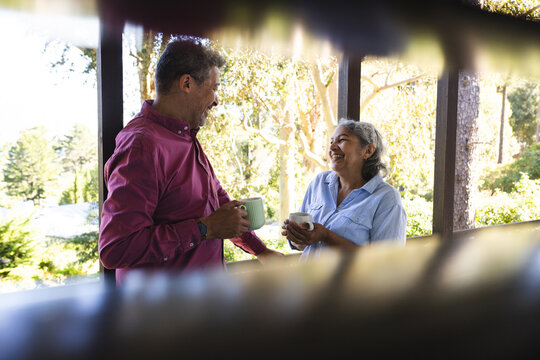 Senior biracial couple enjoys a warm conversation with coffee - Powered by Adobe